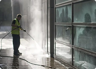 Pressure washing worker is clearning a building wall